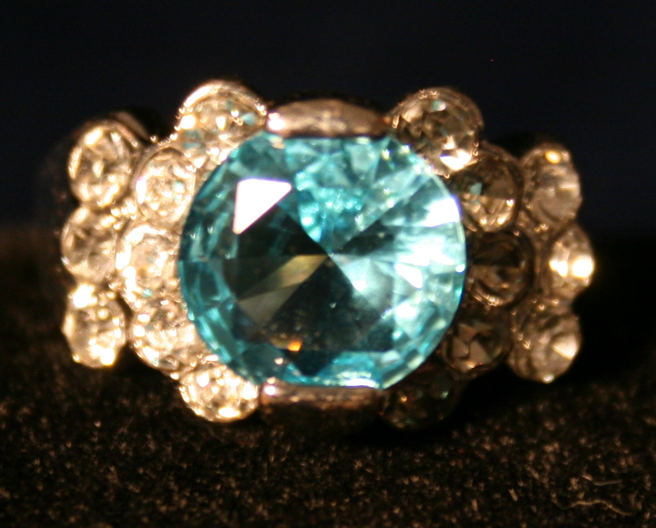 central blue gemstone surrounded by smaller clear gemstones.