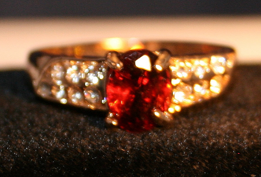 Oval Red gemstone with clear gemstones arranged in rows on the band