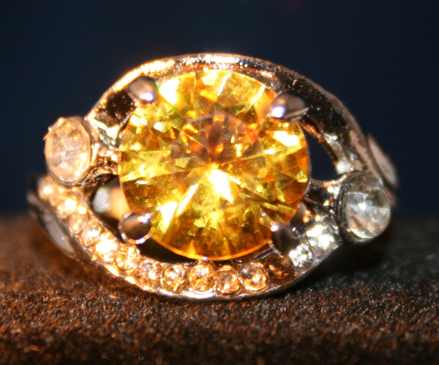 Yellow round gemstone surrounded by clear stones in silver setting