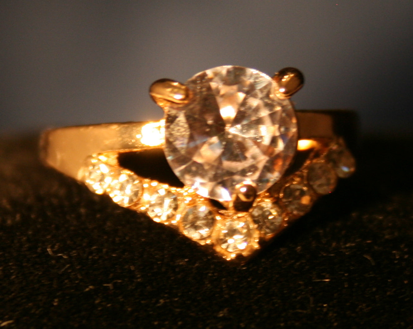 round clear gemstone with a V-shaped band with inlaid stones
