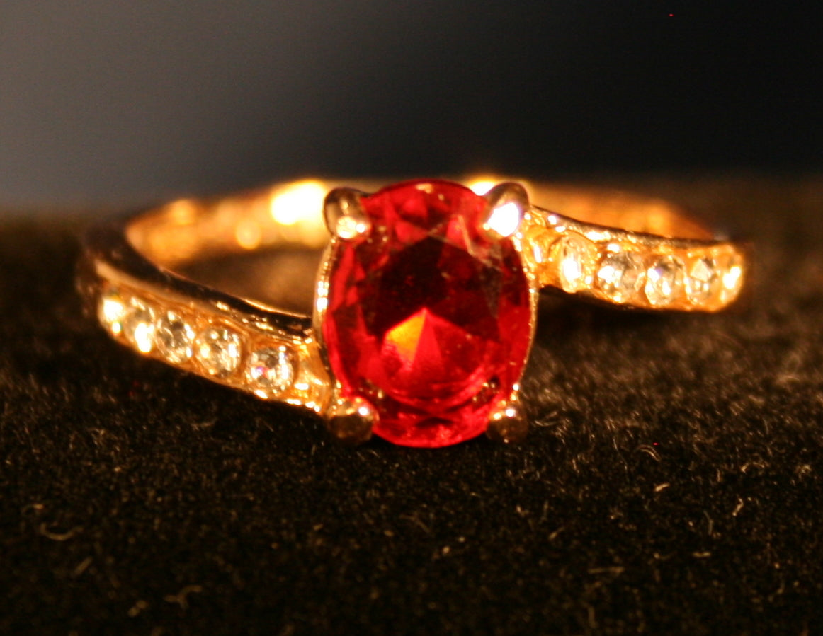 Red gemstone with offset band and clear stones inlaid.