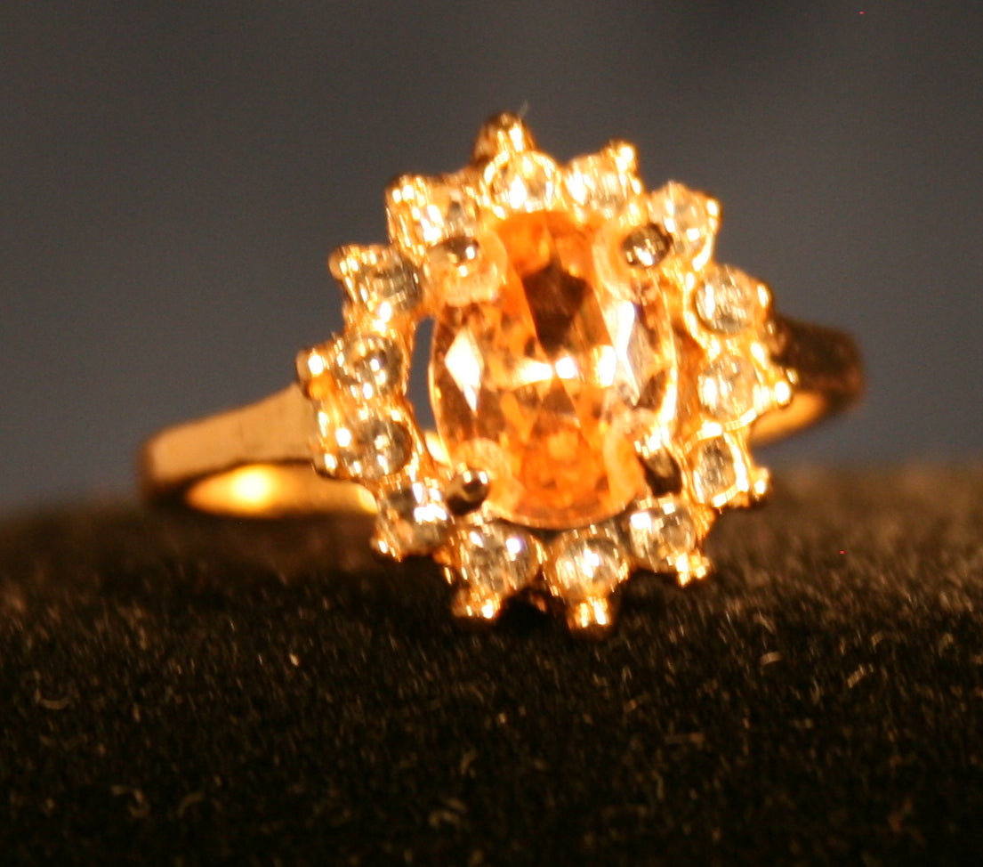 central gemstone is surrounded by a halo of smaller clear gemstones,