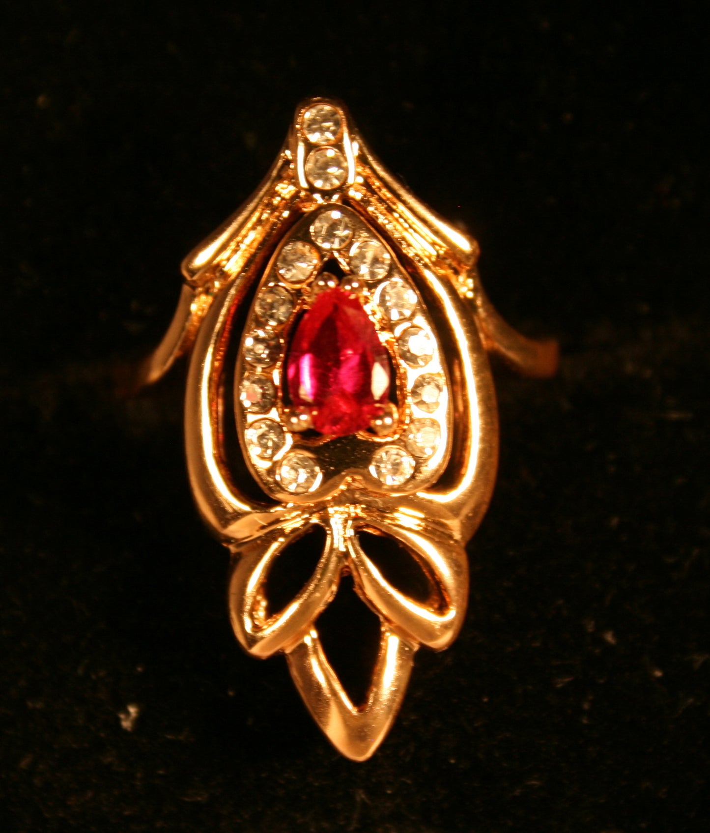 ornate gold ring with a central red gemstone,