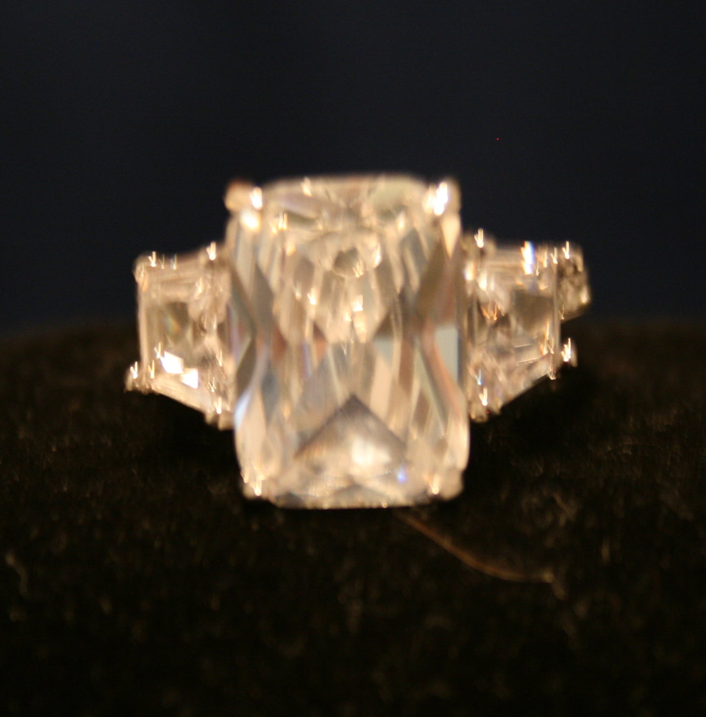 large, square-cut central gemstone, flanked by two smaller square-cut gemstones on either side