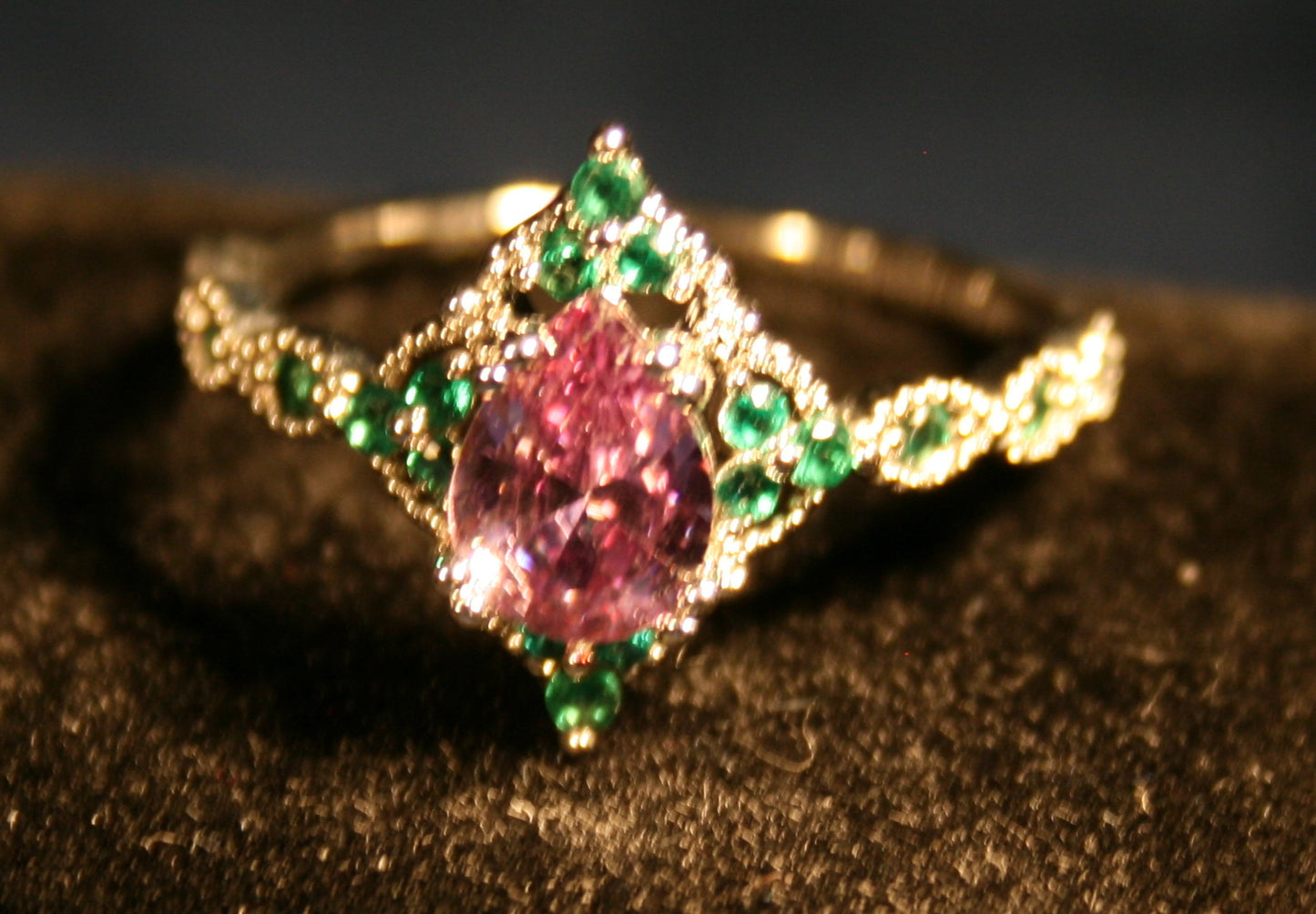 Tear Drop Pinkish center gemstone surrounded by green gemstones